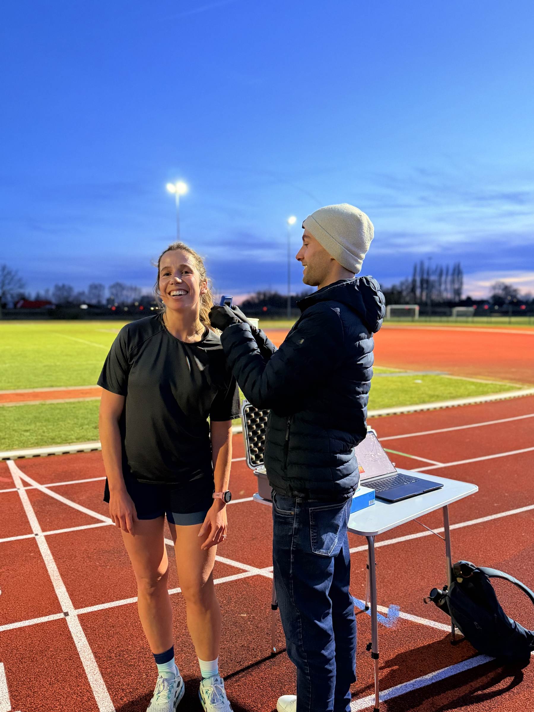 Sven Vandenbroucke neemt een lactaatstaal bij een loopster op de atletiekpiste