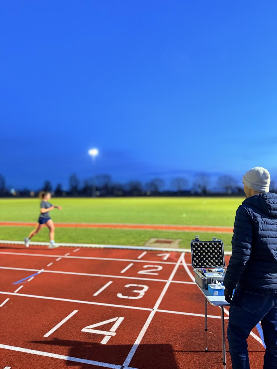Veldtest op de atletiekpiste bij valavond, met de meetkoffer naast de baan